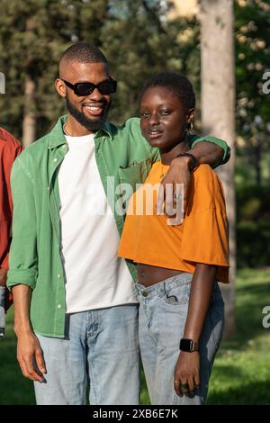 Heureux étudiant afro-américain souriant embrassant sa petite amie debout à l'extérieur regardant la caméra. Banque D'Images