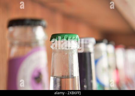 Les bouteilles de boisson vintage avec des bouchons colorés sur l'étagère du bar créent un affichage de boissons rétro nostalgique Banque D'Images