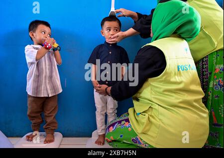 Jakarta, Indonésie. 11 juin 2024. Les membres du personnel mesurent la taille d'un enfant lors d'un programme de prévention du retard de croissance chez l'enfant à Jakarta, en Indonésie, le 11 juin 2024. Crédit : Zulkarnain/Xinhua/Alamy Live News Banque D'Images