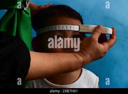 Jakarta, Indonésie. 11 juin 2024. Un membre du personnel mesure le périmètre crânien d'un enfant au cours d'un programme de prévention du retard de croissance chez l'enfant à Jakarta, en Indonésie, le 11 juin 2024. Crédit : Zulkarnain/Xinhua/Alamy Live News Banque D'Images