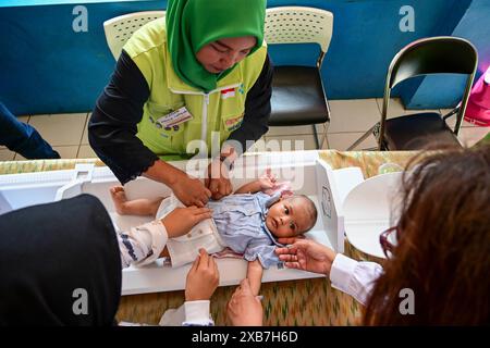 Jakarta, Indonésie. 11 juin 2024. Un membre du personnel pèse un jeune enfant pendant un programme de prévention du retard de croissance chez les enfants à Jakarta, en Indonésie, le 11 juin 2024. Crédit : Zulkarnain/Xinhua/Alamy Live News Banque D'Images