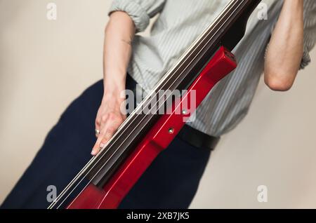 Un homme jouant de la contrebasse électrique rouge. Gros plan avec mise au point sélective. Fond de photo de musique live Banque D'Images