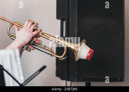 Trompette avec sourdine droite dans les mains du trompettiste. Photo de fond de musique live Banque D'Images