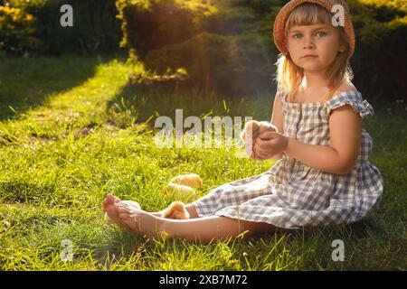 Petite fille avec des poussins mignons sur l'herbe verte à l'extérieur. Bébés animaux Banque D'Images