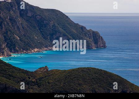 Une vue panoramique sur la plage avec des bateaux sur l'océan près de hautes montagnes couvertes de forêts Banque D'Images