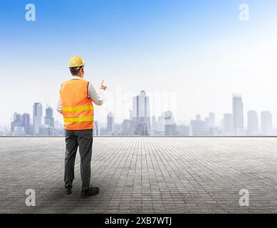 Concept d'entreprise de construction avec point de doigt d'ingénieur civil de vue arrière sur fond de paysage urbain Banque D'Images