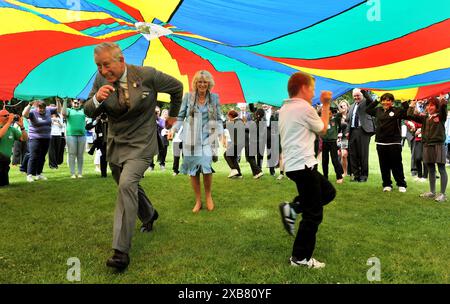 Photo du dossier datée du 19/07/12 du prince de Galles et de la duchesse de Cornouailles courant sous un parachute aux couleurs vives lors d'un rassemblement de jeunes au parc Saumarez à Guernesey, alors qu'ils poursuivent leur visite dans les îles Anglo-Normandes. Le roi Charles III et la reine Camilla doivent effectuer une visite estivale dans les îles Anglo-Normandes. Ils se rendront à Jersey le 15 juillet, puis à Guernesey le 16 juillet pour le voyage dénonciateur de deux jours, ont annoncé les États de Jersey et de Guernesey. Date d'émission : mardi 11 juin 2024. Banque D'Images