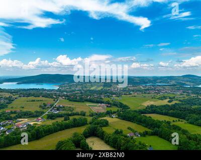 Une vue aérienne des villages, du lac et de belles collines verdoyantes sous un ciel bleu Banque D'Images