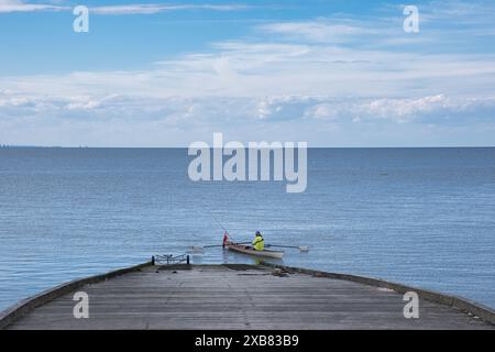 Rameur solitaire dans son bateau à Whitstable, Kent au début du printemps Banque D'Images