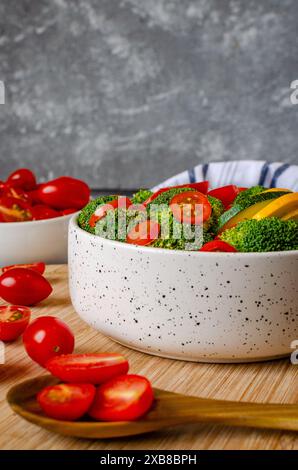 Bol de légumes frais, y compris tomates, brocoli et concombre, à côté d'autres bols Banque D'Images