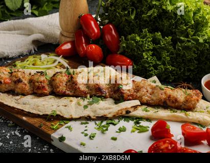 Un ensemble de table avec un délicieux plateau de kebab de viandes assorties et de légumes frais Banque D'Images