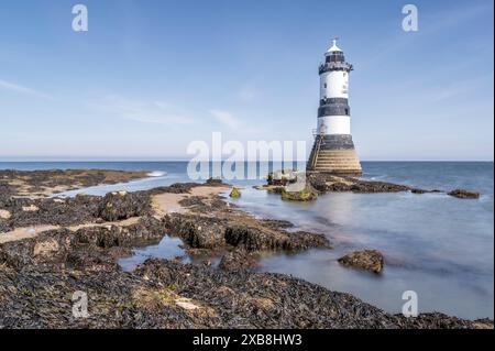 Phare sur le bord d'un promontoire rocheux. Le phare est situé à Penmon point, Angelsey, au nord du pays de Galles. La journée est ensoleillée Banque D'Images