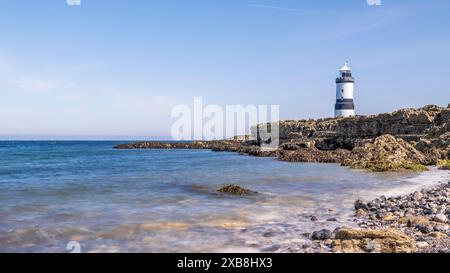 Phare sur le bord d'un promontoire rocheux. Le phare est situé à Penmon point, Angelsey, au nord du pays de Galles. La journée est ensoleillée Banque D'Images