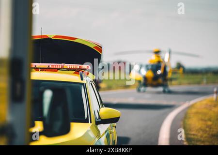 Focalisation sélective sur le clignotant de lumière rouge sur le toit de la voiture d'ambulance du service médical d'urgence contre l'atterrissage d'hélicoptère sur la route. Thèmes sauvetage, urgence Banque D'Images