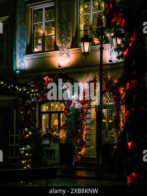 Une scène de rue festive avec des fenêtres éclairées dans un grand bâtiment pendant Noël Banque D'Images