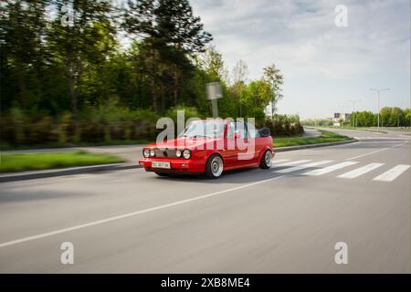 Red Volkswagen Golf mk2 cabriolet conduite sur une route rurale. Vue de trois quarts de face de la voiture rouge des années 1980 dans un cadre de campagne. Banque D'Images