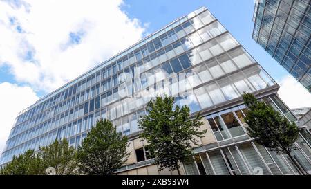 DAS Gebaeude Gebäude der Sparkasse Siegen. Der Himmel ist blau mit ein paar Wolken die sich in den Scheiben spiegeln. IM Vordergrund stehen Baeume Bäume mit gruenen grünen Blaettern Blättern. Sparkasse AM 11.06.2024 à Siegen/Deutschland. *** Le bâtiment de la Sparkasse Siegen le ciel est bleu avec quelques nuages reflétés dans les fenêtres au premier plan sont des arbres arbres avec des feuilles vertes Sparkasse le 11 06 2024 à Siegen Allemagne Banque D'Images