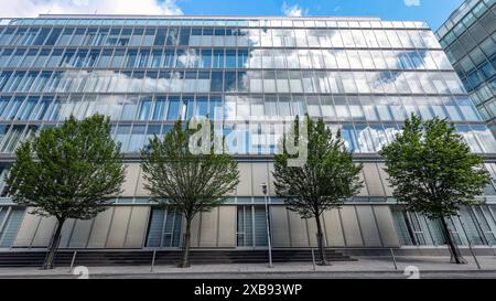 DAS Gebaeude Gebäude der Sparkasse Siegen. Der Himmel ist blau mit ein paar Wolken die sich in den Scheiben spiegeln. IM Vordergrund stehen Baeume Bäume mit gruenen grünen Blaettern Blättern. Sparkasse AM 11.06.2024 à Siegen/Deutschland. *** Le bâtiment de la Sparkasse Siegen le ciel est bleu avec quelques nuages reflétés dans les fenêtres au premier plan sont des arbres arbres avec des feuilles vertes Sparkasse le 11 06 2024 à Siegen Allemagne Banque D'Images