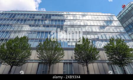 DAS Gebaeude Gebäude der Sparkasse Siegen. Der Himmel ist blau mit ein paar Wolken die sich in den Scheiben spiegeln. IM Vordergrund stehen Baeume Bäume mit gruenen grünen Blaettern Blättern. Sparkasse AM 11.06.2024 à Siegen/Deutschland. *** Le bâtiment de la Sparkasse Siegen le ciel est bleu avec quelques nuages reflétés dans les fenêtres au premier plan sont des arbres arbres avec des feuilles vertes Sparkasse le 11 06 2024 à Siegen Allemagne Banque D'Images