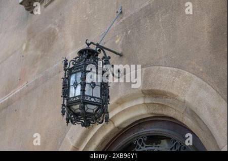 Détail d'une lampe en fer forgé ancienne et ornée suspendue au-dessus de l'entrée d'une vieille maison en pierre à Barcelone. Banque D'Images