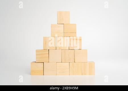 Les blocs de cube en bois vierges vides construisent une forme pyramidale avec le grand sur le dessus, isolé sur le bureau en bois sur fond blanc. Processus de croissance de l'entreprise, educat Banque D'Images