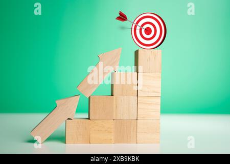 Icône de cible sur le dessus des blocs de bois avec des flèches de montée, des étapes de graphique à barres 3d sur fond vert, processus de croissance des affaires, profit, investissement, ec Banque D'Images