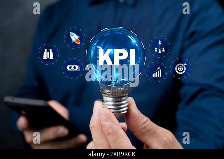 L'homme tient une ampoule. Indicateur de performance clé (KPI) utilisant des indicateurs de Business Intelligence (BI) pour mesurer les réalisations par rapport à l'objectif planifié, Banque D'Images