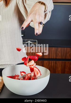 Femme préparant le dessert de fraise fraîche dans White Bowl dans Home Kitchen. Banque D'Images