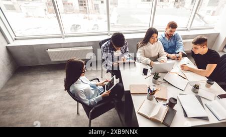 Groupe de personnes assis autour de la table dans le bureau, vue ci-dessus Banque D'Images