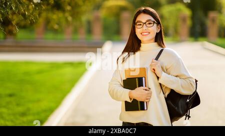 Étudiant universitaire marchant avec sac à dos et livres Banque D'Images