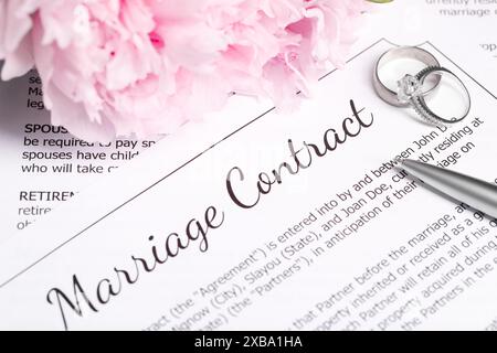 Contrat de mariage, alliances, stylo et fleurs sur table, gros plan Banque D'Images