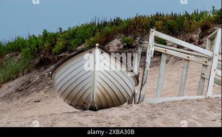Un bateau White Lifeguard's Row échoue sur une côte de sable à côté d'un stand de sauveteur qui est couché dans une dune de sable à Gilgo Beach. Banque D'Images