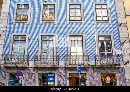Façade d'un bâtiment recouverte de tuiles. Un signe d'ATM est vu à l'étage inférieur. Banque D'Images