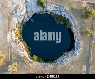 Vue aérienne du Little Blue Lake à Mount Gambier, Australie, avec une eau bleue claire entourée de terrains rocheux Banque D'Images