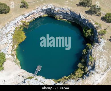 Vue aérienne du Little Blue Lake à Mount Gambier, Australie, avec une eau bleue claire entourée de terrains rocheux Banque D'Images