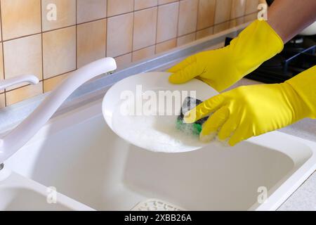 Laver la vaisselle. Les mains avec une éponge laver le plat sous l'eau courante Banque D'Images