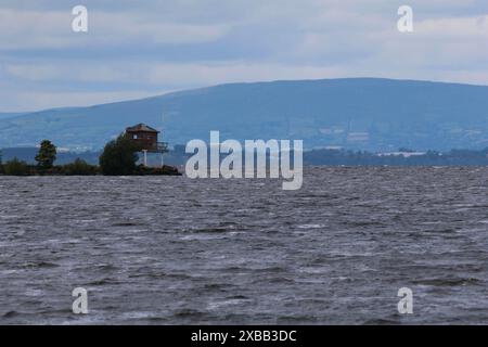 South Shore Lough Neagh, County Armagh, Irlande du Nord, Royaume-Uni. 11 juin 2024. Météo britannique - près de la mi-juin et une autre journée froide pour la période de l'année dans le flux d'air nord. Ciel gris avec l'éclatement occasionnel de la lumière du soleil a vu des températures autour de 12C aujourd'hui. Le flux d'air plus froid a apporté une visibilité accrue avec un air plus clair - champs sur les montagnes Sperrin clairement visibles. Crédit : CAZIMB/Alamy Live News. Banque D'Images