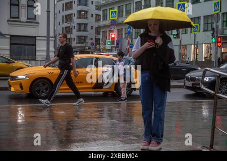 Moscou, Russie. 11 juin 2024. Une femme se réfugie sous un parapluie pendant la pluie dans le centre de Moscou, en Russie Banque D'Images