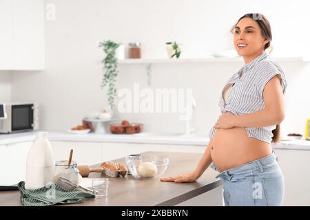 Jeune femme enceinte préparant la pâte dans la cuisine Banque D'Images