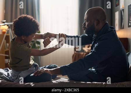 Portrait vue de côté d'un père afro-américain essayant de calmer son fils adolescent et tenant ses bras dans un combat hystérique Banque D'Images