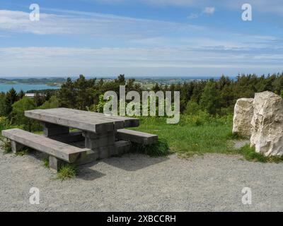 Table et banc en bois sur un chemin de gravier avec vue sur la forêt et la mer sous un ciel légèrement nuageux, Stavanger, Norvège, Scandinavie Banque D'Images