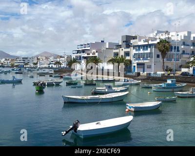 Un port tranquille avec de nombreux bateaux dans l'eau, entouré de bâtiments blancs et de palmiers sous un ciel bleu partiellement nuageux, arrrecife, lanzaorte Banque D'Images