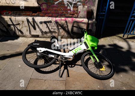 Lime est le plus grand fournisseur de véhicules électriques partagés au monde. Cette image représente un vélo électrique de marque Lime jeté dans une rue de Londres, au Royaume-Uni Banque D'Images