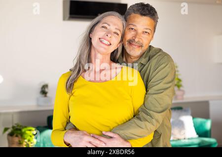 Un couple biracial mature sourit chaleureusement tout en s’embrassant, à la maison Banque D'Images