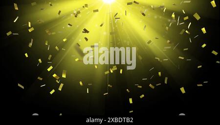 Image de confettis tombant sur la lumière jaune sur fond noir Banque D'Images