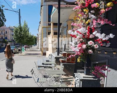 Non exclusif : KHARKIV, UKRAINE - 8 JUIN 2024 - Une femme passe devant un café en plein air, Kharkiv, dans le nord-est de l'Ukraine. Banque D'Images