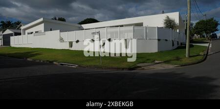 Maison contemporaine, design construite sur un bloc d'angle, bâtiment blanc en retrait de la rue blanc mur de soutènement bas, clôture en bois, Carina Australie Banque D'Images