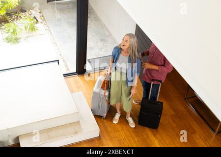 Couple biracial mature arrivent à la maison de vacances avec des valises Banque D'Images