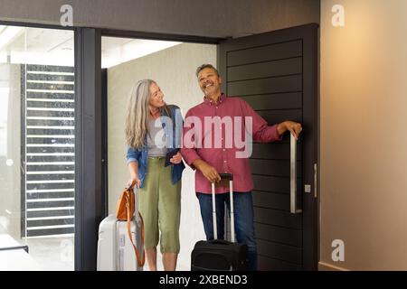 Couple biracial mature arrivent à la maison de vacances avec des valises Banque D'Images