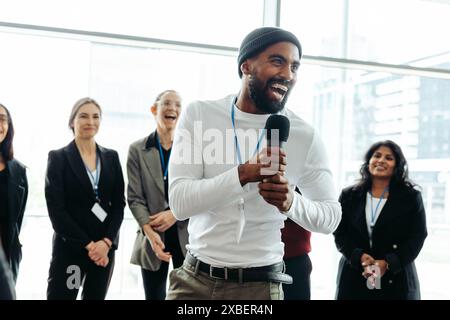 Une conférence d'entreprise dynamique avec un homme d'affaires joyeux parlant et s'engageant avec une équipe enthousiaste. Banque D'Images